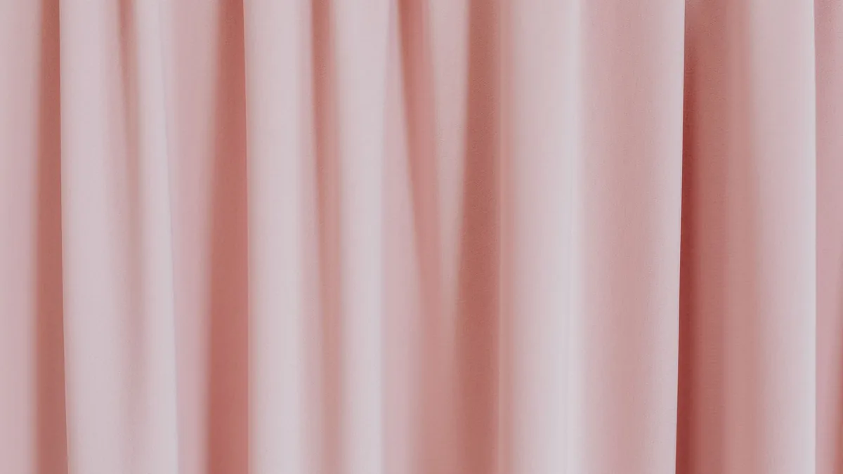 Detalle de una cortina rosa claro donde se aprecian la textura del tejido y los pliegues de la caída.